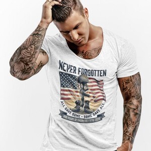 May include: White t-shirt featuring a graphic with an American flag, helmet, boots, and the text "Never Forgotten." The design includes the phrases "All Gave Some, Some Gave All" and "250 Years of Sacrifice - 1776-2026."