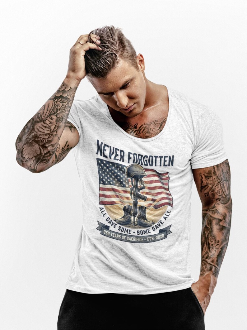 May include: White t-shirt featuring a graphic with an American flag, helmet, boots, and the text "Never Forgotten." The design includes the phrases "All Gave Some, Some Gave All" and "250 Years of Sacrifice - 1776-2026."
