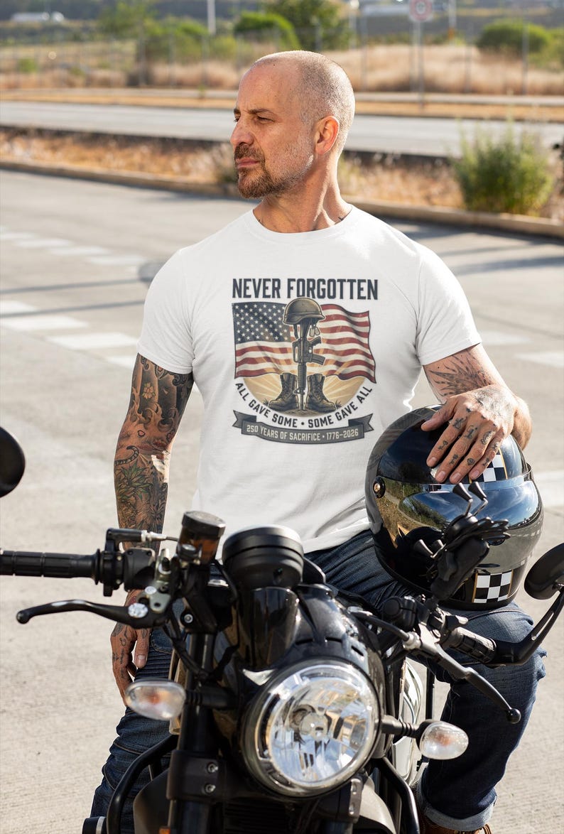 May include: White t-shirt with the text "NEVER FORGOTTEN" above an American flag and a soldier's memorial. The shirt also features the text "ALL GAVE SOME - SOME GAVE ALL" and "250 YEARS OF SACRIFICE - 1776-2026".