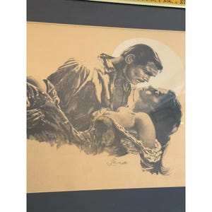 May include: A framed charcoal-style illustration on tan paper depicting a man holding a woman in his arms. The artwork features a circular light background behind the figures and includes the signature "Lanse" in the lower center of the drawing.