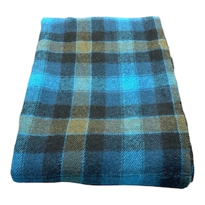 Pode incluir: Cobertor xadrez azul, preto e castanho dobrado. O cobertor apresenta um padr&atilde;o xadrez cl&aacute;ssico com uma mistura de quadrados azuis, pretos e castanhos. O tecido parece ser um material macio e tecido.