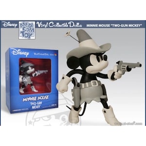 Pu&ograve; includere: Una bambola da collezione in vinile di Minnie Mouse in bianco e nero, in un abito da cowboy, che tiene in mano una pistola. La bambola &egrave; in una scatola con le parole "Minnie Mouse Two-Gun Mickey". La scatola &egrave; blu con il logo Disney.