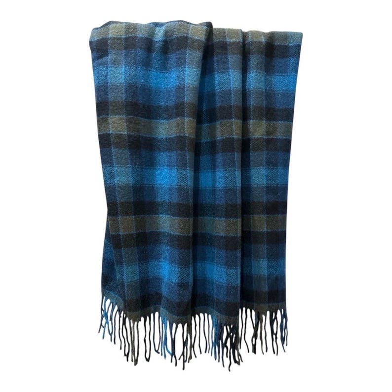 Pode incluir: Um cobertor xadrez azul, cinza e preto com franjas. O cobertor apresenta um padr&atilde;o xadrez cl&aacute;ssico em tons de azul, cinza e preto. A franja &eacute; preta e pende da borda inferior do cobertor.