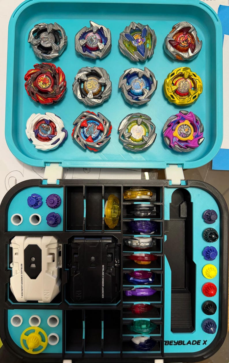 May include: A teal carrying case filled with colorful spinning tops. The case is open, revealing multiple tops in various designs and colors, along with launchers and accessories. The text "BEYBLADE X" is visible.