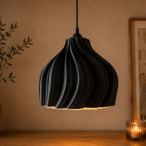 May include: A matte black pendant light fixture featuring a distinct spiraling, ribbed texture that curves from the top down to the wide opening. The lamp is suspended by a thin black cord and emits a warm glow from its interior base.