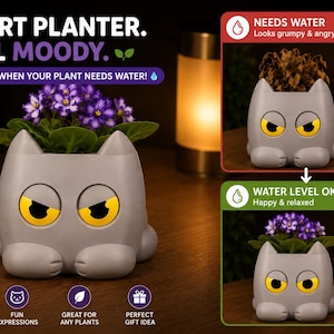 May include: A gray cat-shaped planter with yellow eyes that change expression based on soil moisture. Text reads: SMART PLANTER. REAL MOODY. IT KNOWS WHEN YOUR PLANT NEEDS WATER! Includes visual indicators for NEEDS WATER and WATER LEVEL OK states.