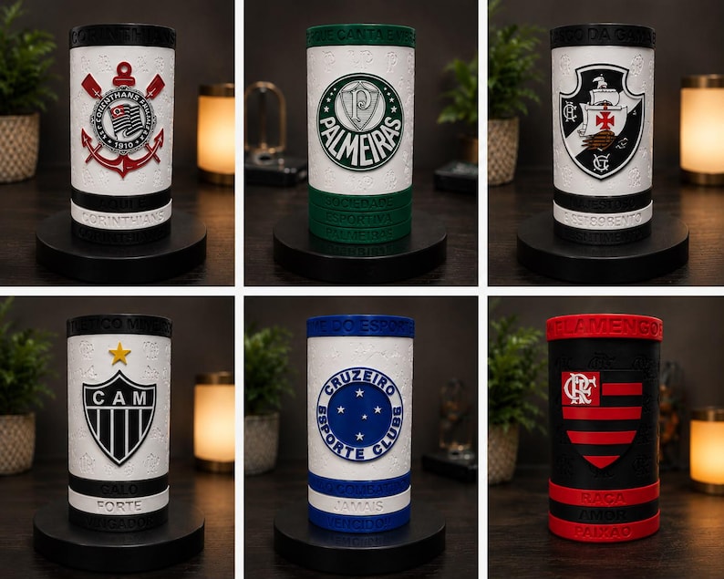 May include: Cylindrical drink holders with team logos and colours. The holders are white with black accents and sit on black bases. Logos include a cross, a star, and a shield. Each has text at the base.