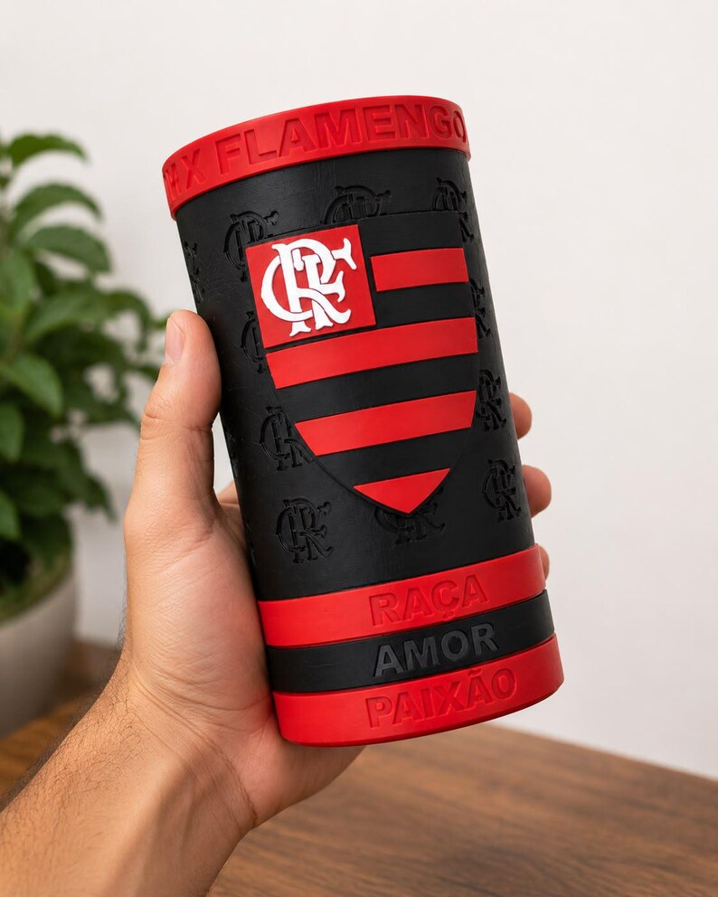 May include: A black and red cylindrical container with the text "FLAMENGO" on the rim. The container features the Flamengo team logo and the words "RACA AMOR PAIXAO".