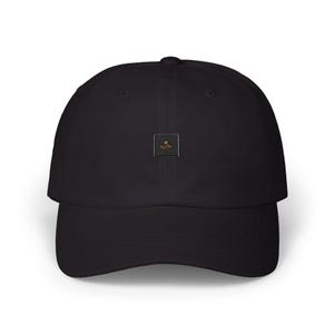 May include: A solid black baseball cap featuring a small, centered square patch. The patch is black with a gold-colored graphic of a palm tree and the text "PALM PALM" printed in a stylized font, positioned above a small gold dot.