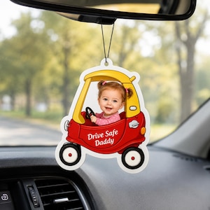Peut inclure: Un désodorisant de voiture suspendu avec l'image d'un enfant dans une voiture jouet rouge et jaune. Le texte Drive Safe Daddy est imprimé en blanc sur le côté de la voiture. L'ornement est suspendu par un fin cordon noir au rétroviseur.
