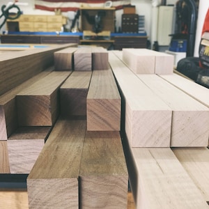 Peut inclure: Gros plan sur une pile de planches de bois, certaines sont brun clair et d'autres brun fonc&eacute;. Les planches sont dispos&eacute;es en quinconce.