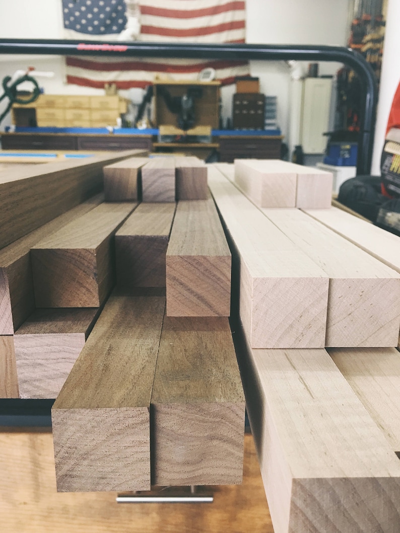 Peut inclure: Gros plan sur une pile de planches de bois, certaines sont brun clair et d'autres brun fonc&eacute;. Les planches sont dispos&eacute;es en quinconce.
