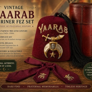 May include: A vintage Yaarab Shrine Fez set, including a burgundy fez hat with gold embroidery, a matching tie, and a leather storage case. The hat features the word "Yaarab" and a crescent moon and star emblem. Dating from the 1940s to 1960s.