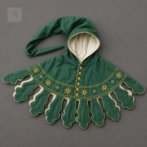 May include: A green hooded cape with a long, pointed hood and a scalloped hemline. The cape features gold star embroidery and yellow buttons down the front. The interior lining is a cream color.