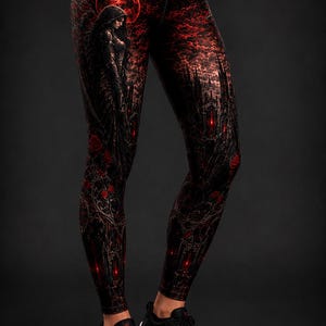 May include: High-waisted leggings featuring a dark, gothic-inspired print with a red moon, a silhouetted figure with wings, and intricate architectural elements. The design incorporates deep black and vibrant red tones with floral accents.