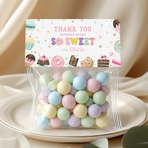 May include: A clear plastic treat bag filled with round pastel-colored candies, topped with a white cardstock header featuring colorful illustrations of sweets and the text Thank You For Making My Birthday So Sweet Love Olivia.