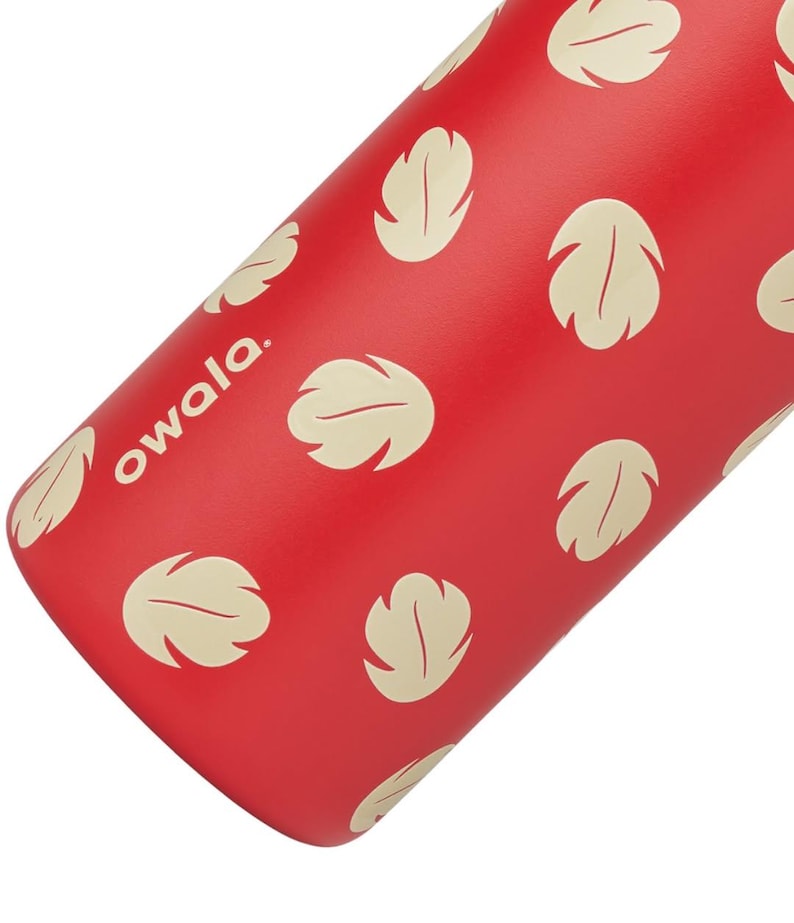 May include: Red water bottle with a pattern of cream-colored leaf shapes. The word "owala" is printed in white on the side of the bottle. The bottle is cylindrical and appears to be made of metal.