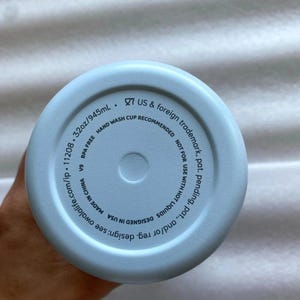 K&ouml;nnte beinhalten: Hellblauer Wasserflaschenboden mit dem Text "32oz/945mL" und "BPA-FREI". Der Boden der Flasche enth&auml;lt auch den Text "HANDW&Auml;SCHE EMPFOHLEN" und "DESIGNED IN USA".