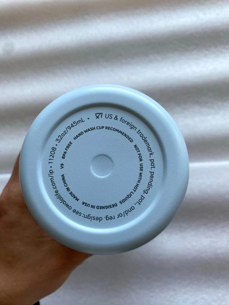 K&ouml;nnte beinhalten: Hellblauer Wasserflaschenboden mit dem Text "32oz/945mL" und "BPA-FREI". Der Boden der Flasche enth&auml;lt auch den Text "HANDW&Auml;SCHE EMPFOHLEN" und "DESIGNED IN USA".
