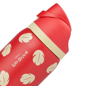 May include: Red Owala water bottle featuring a design inspired by Disney's Lilo & Stitch. The bottle has a red body with cream-colored leaf patterns and a cream-colored band. The text "Disney Lilo & Stitch" is printed on the bottle.