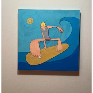 May include: A whimsical painting depicts a surfer riding a wave. The surfer, with a yellow cap and grey top, is on a yellow surfboard. The background features a blue sky, a sun, and a large blue wave. The artwork is on a square canvas.
