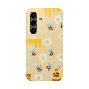 May include: Yellow phone case featuring a whimsical design of bees, daisies, and honey. The case has a light yellow background with a pattern of white daisies and cartoon bees with blue wings. Honey drips from the top, and a honey pot is at the bottom.
