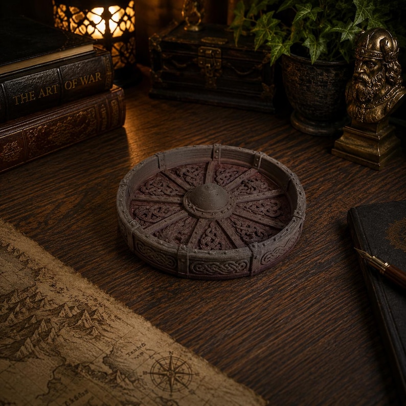 May include: A circular tray featuring a raised rim and a central hub with radiating spokes. The surface is decorated with intricate, embossed Celtic knotwork patterns in a weathered, dark brown finish, resembling a stylized ancient wagon wheel.