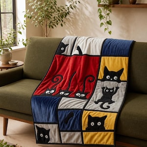 May include: A rectangular throw blanket featuring a patchwork design of black cat illustrations on solid color blocks of red, yellow, blue, and gray. The cats are depicted in various poses, including peeking, hanging, and sitting, with white eyes.