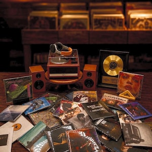 May include: A collection of various music CDs scattered on a surface, featuring a portable record player with headphones, two small speakers, and a gold record award. The CD covers display diverse artwork, including The Smashing Pumpkins and others.