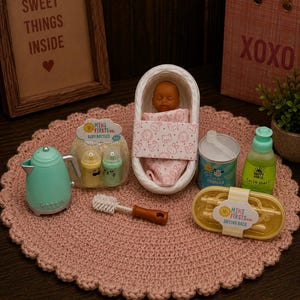 May include: A miniature toy set featuring a doll in a white bassinet, a light blue kettle, two baby bottles labeled Mini Firsts Co., a bottle brush, a container of formula, a bottle of dish soap, and a yellow drying rack labeled Mini Firsts Co.