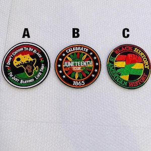 May include: Three round embroidered patches with black borders. Patch A has text "I didn't choose to be black, I'm just blessed like that" around a black and gold map of Africa. Patch B says "Celebrate Juneteenth 1865". Patch C says "Black History American History".