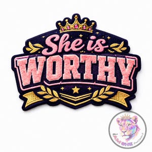 May include: Embroidered patch with the words "She is WORTHY" in pink, outlined in a darker pink, on a navy blue background. The patch features a gold crown, stars, and laurel leaves. A circular logo with a lioness wearing a crown is in the bottom right corner.