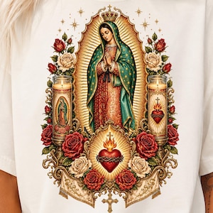 May include: An off-white t-shirt featuring a detailed graphic of the Virgin of Guadalupe in a teal and red robe, surrounded by red and white roses, two lit prayer candles, and a central flaming sacred heart with a crown of thorns.