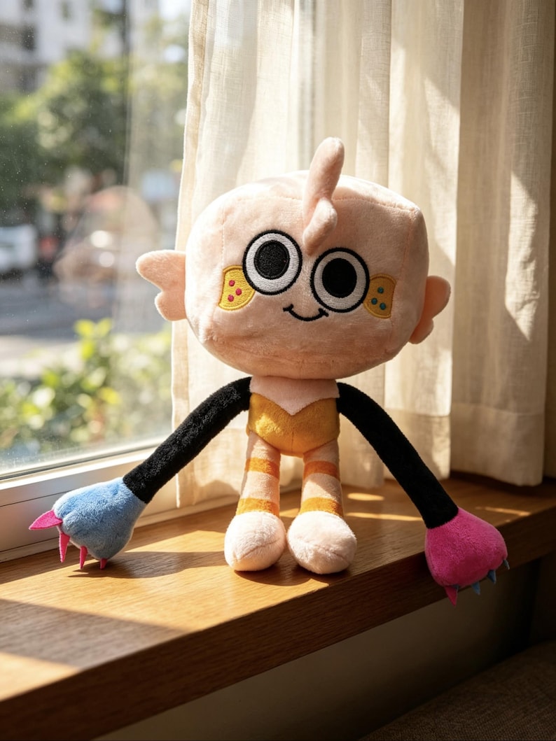 May include: A plush toy with a large, round, light peach-colored head, black and white eyes, and a small smile. It has long black arms ending in one blue and one pink paw with small claws, and legs with orange stripes and a yellow torso.