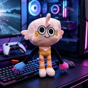 May include: A plush toy with a large, square-shaped head, wide black and white eyes, and a small embroidered smile. It has thin black arms ending in one blue and one pink hand with claws, and legs with orange stripes, standing on a black surface.