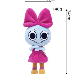 May include: A plush doll with a light blue head, large black eyes, and a wide grin. It wears a large pink bow on its head and a matching pink dress. The doll has orange feet and measures 15 cm in width, 34 cm in height, and weighs 140 grams.