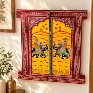 May include: A rectangular wooden wall hanging designed like a window frame with two hinged doors. The frame is painted deep red with white line patterns. The yellow panels feature hand-painted scenes of figures riding elephants under palm trees.
