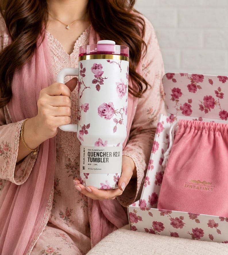 May include: White tumbler with a floral rose pattern, a pink lid, and a handle. The tumbler is labeled "QUENCHER H2.0 TUMBLER" and comes with a pink drawstring bag and a floral-patterned box. The tumbler is 40 oz / 1.18 L.