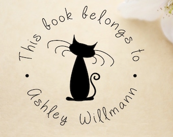 May include: A black and white stamp with a silhouette of a cat and the text "This book belongs to Ashley Willmann".