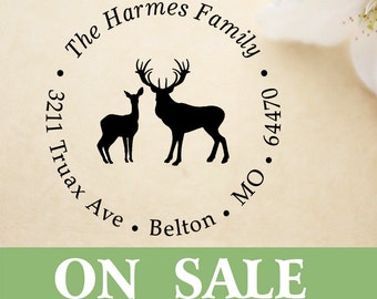 May include: A round stamp with the text "The Harmes Family" encircling a silhouette of a deer and a fawn. The address "3211 Truax Ave, Belton, MO 64470" is also included. The words "ON SALE" are displayed in a green banner.