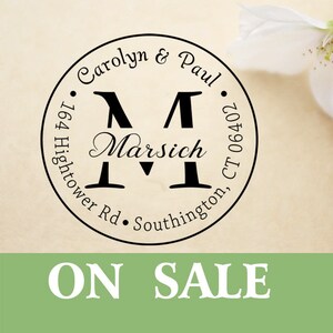 Könnte beinhalten: Ein kreisförmiges Stempeldesign mit den Namen "Carolyn & Paul" und dem Nachnamen "Marsich" in einer dekorativen Schriftart. Die Adresse "164 Hightower Rd. Southington, CT 06402" ist ebenfalls enthalten. Die Worte "ON SALE" werden in einem grünen Banner angezeigt.