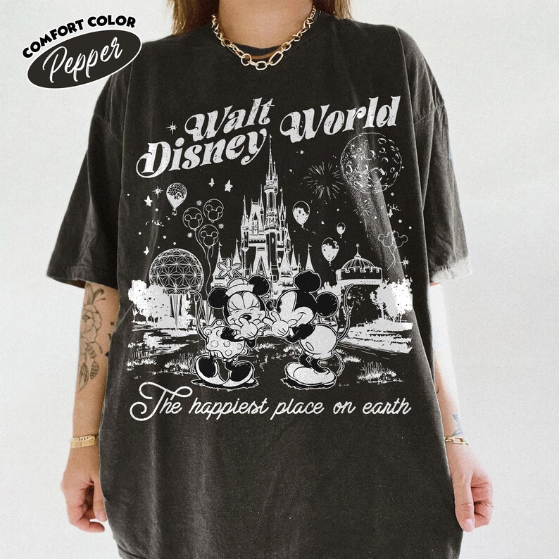 May include: Dark gray Comfort Colors t-shirt with a Walt Disney World graphic. The design features Mickey and Minnie Mouse, Cinderella's castle, and the phrase "The happiest place on earth."