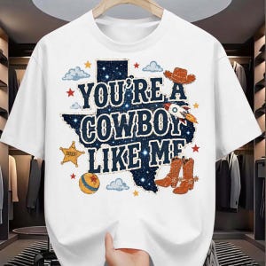 May include: A white short-sleeved t-shirt featuring a graphic of the state of Texas filled with a starry night sky pattern. The text reads YOU'RE A COWBOY LIKE ME, surrounded by illustrations of a cowboy hat, rocket, sheriff star, and boots.