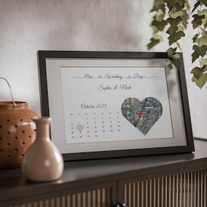 May include: A framed print featuring the text Our Wedding Day, the names Sophia & Noah, and the month October 2025. A calendar grid shows the 14th circled with a red heart, alongside a heart-shaped map graphic with a red location marker pin.