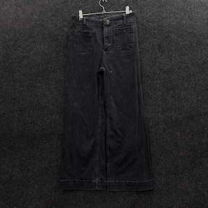 May include: A pair of black denim pants featuring a high-waisted design, a button and zipper fly closure, and two patch pockets on the front. The pants have a wide-leg silhouette with visible stitching along the seams and are hung on a hanger.
