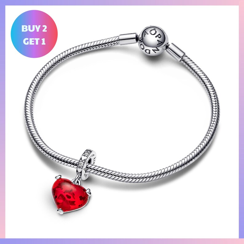 A silver-toned bracelet with a red heart-shaped charm and a silver-toned charm bracelet.