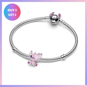A silver bracelet with a charm featuring a pink elephant and a purple elephant.