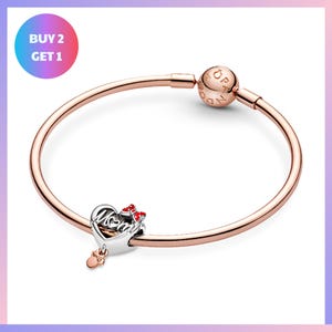 a rose gold-colored bracelet with a charm and a small heart-shaped charm attached to it.