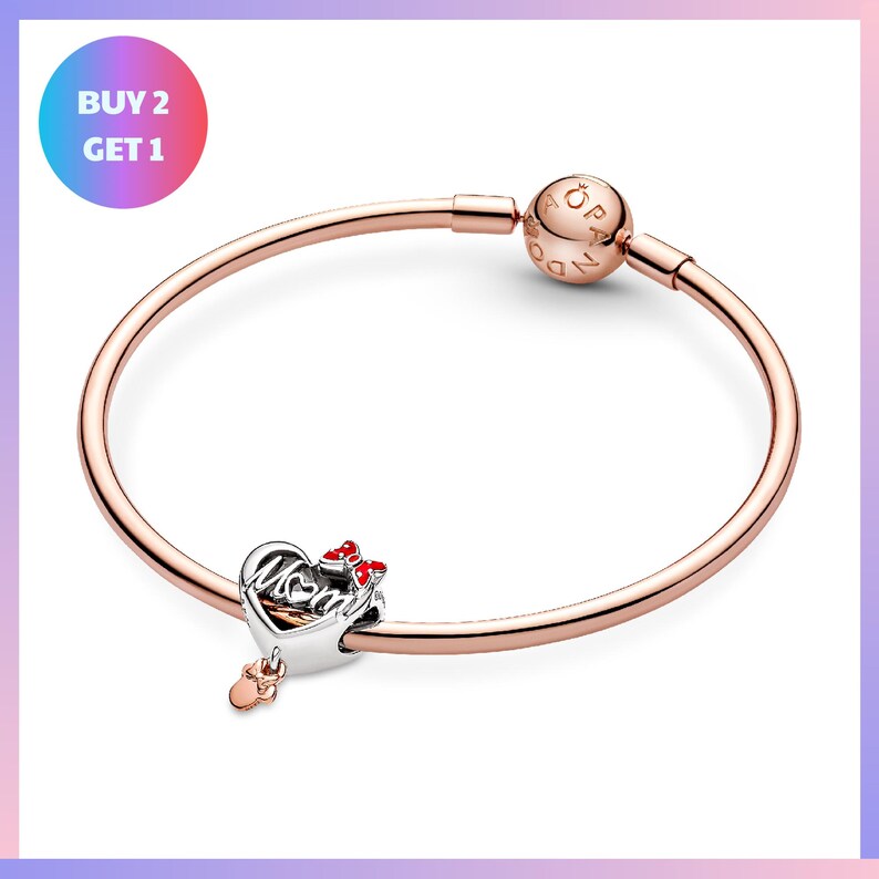 a rose gold-colored bracelet with a charm and a small heart-shaped charm attached to it.