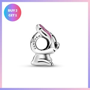 A silver pendant in the shape of a rabbit with a pink ear, sitting on a white background.